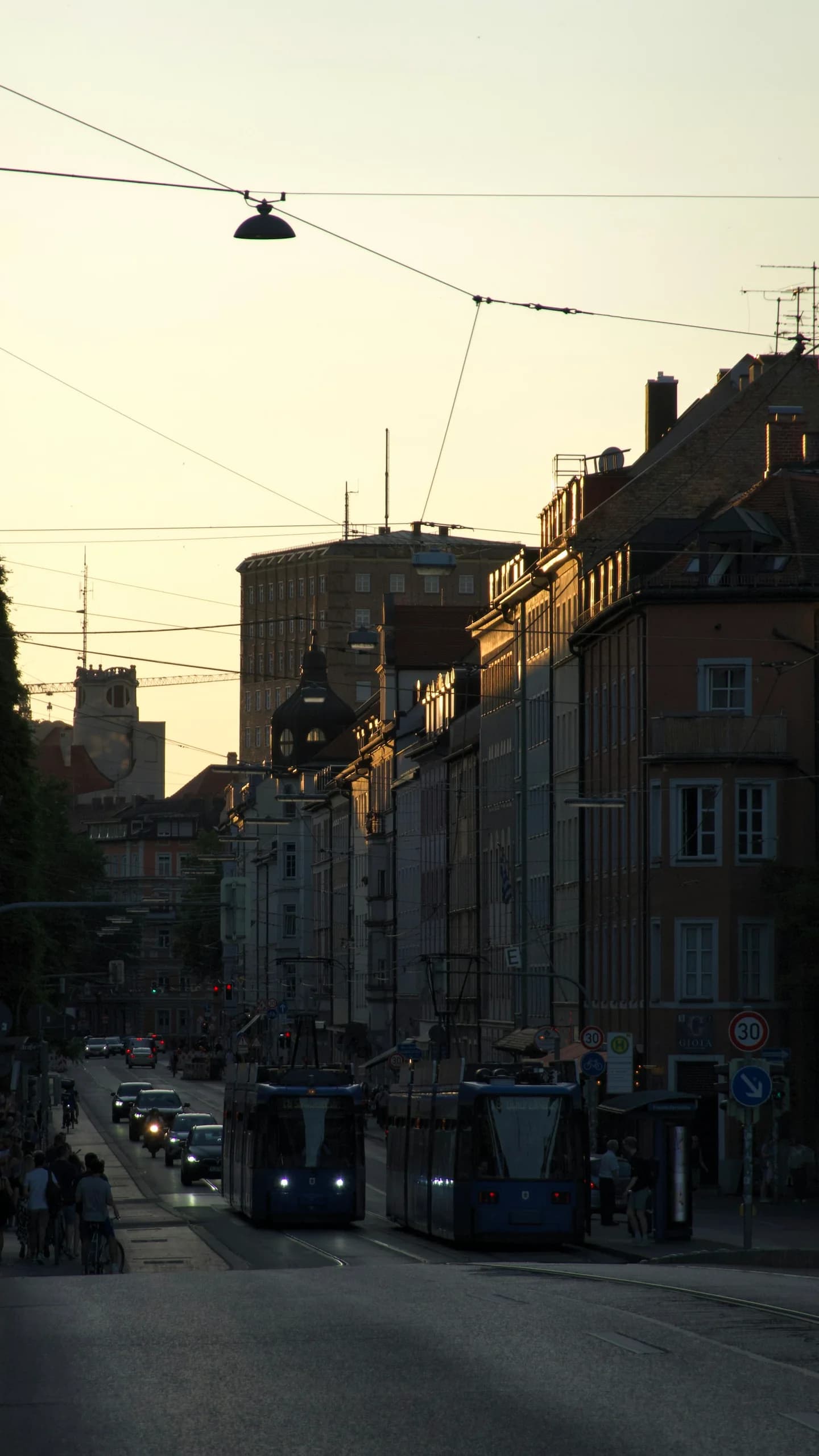 Trams on Fraunhoferstraße in Munich, with historic buildings in the evening light.